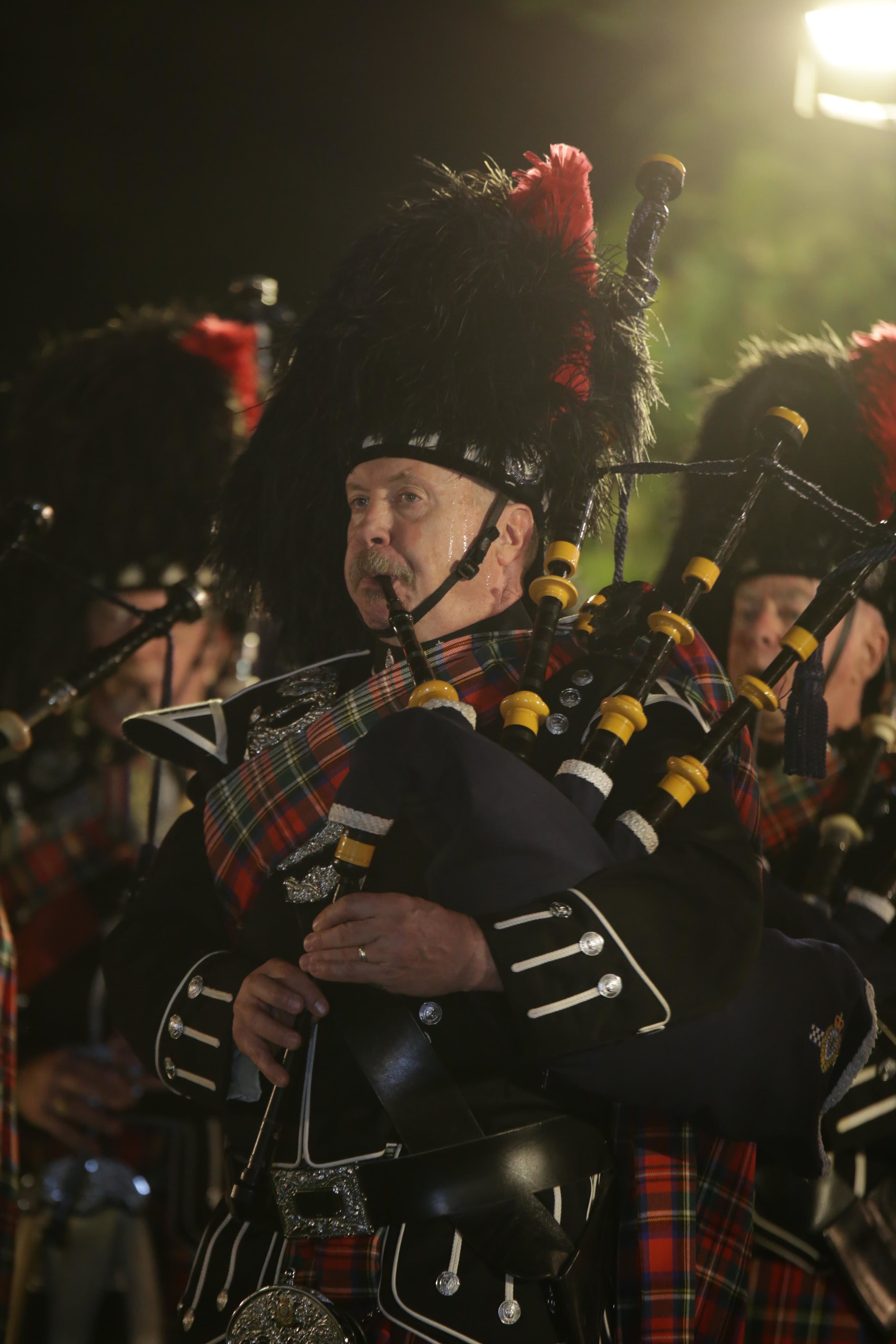 Owen Reid, professional Vancouver bagpiper, performing at a night ceremony in full Highland dress